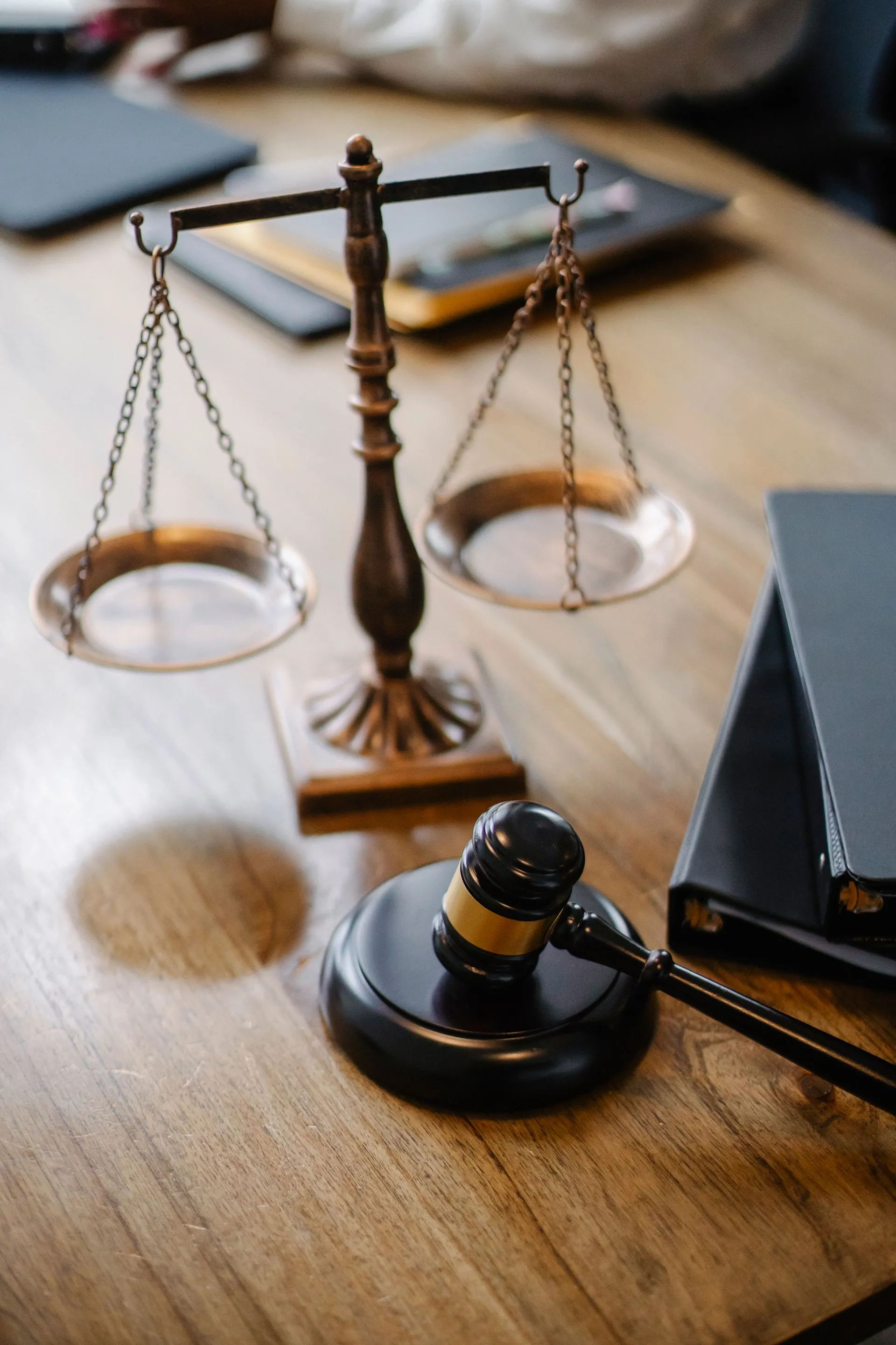 A brass scale of justice and gavel on a wooden desk